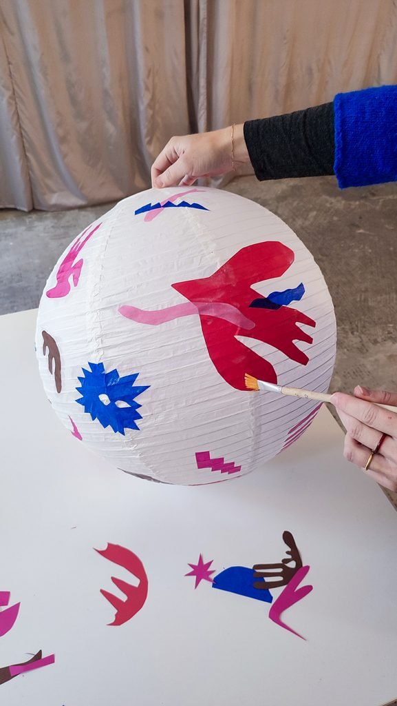 Glueing paper shapes on a paper lamp