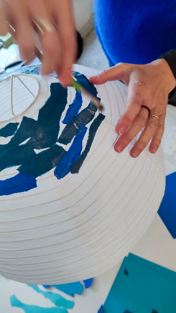 Glueing paper shapes on a paper lamp